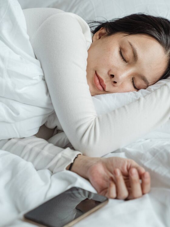 woman sleeping in bed near smartphone